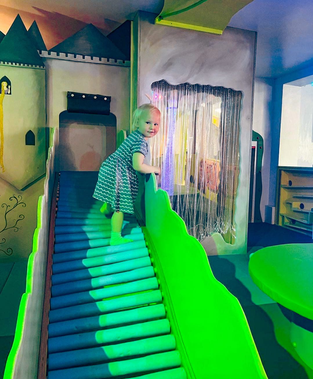 A child climbing the light-up steps to the indoor castle slide